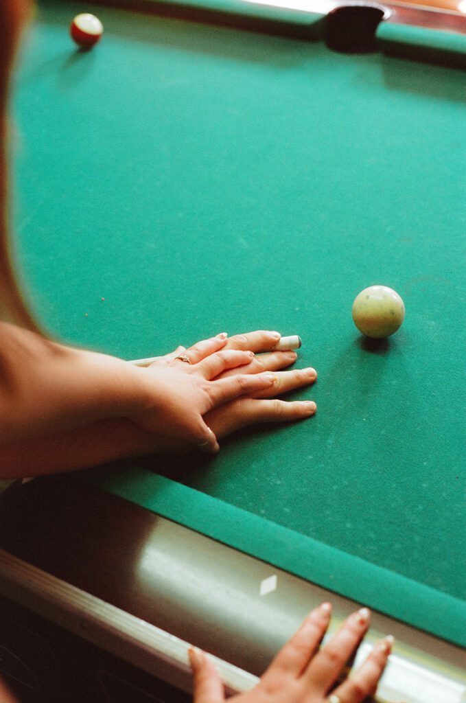 close up of couples hands on pool table at their Minneapolis Engagement photo session