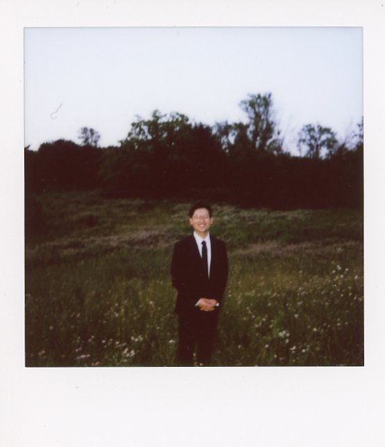 A man wears a black suit in this instant film photo taken to celebrate his 1-year Minnesota elopement anniversary 