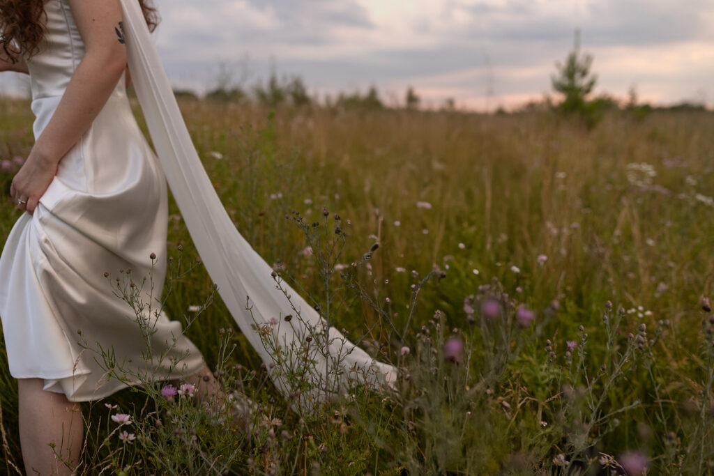 A white dress & purple flowers in a field are photographed by a Minnesota elopement photographer 