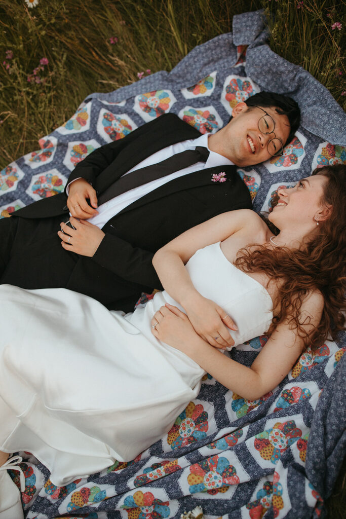 a couple is photographed on a quilt in a field during a minnesota elopement session 