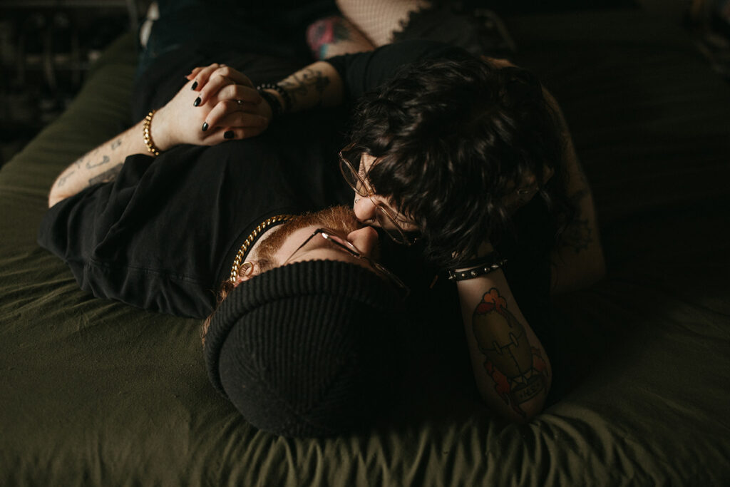 A couple share a kiss on their bed during an in-home engagement session with a Wisconsin photographer. 