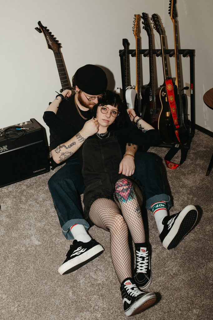 A young couple embraces in their home near their guitar collection during engagement photos in Milwaukee, WI. 