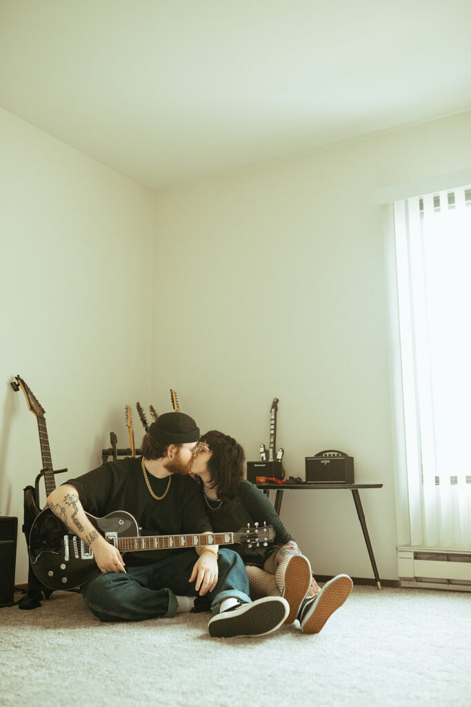 A couple share a kiss on the floor of their apartment during an in-home engagement session with a Wisconsin wedding photographer. 
