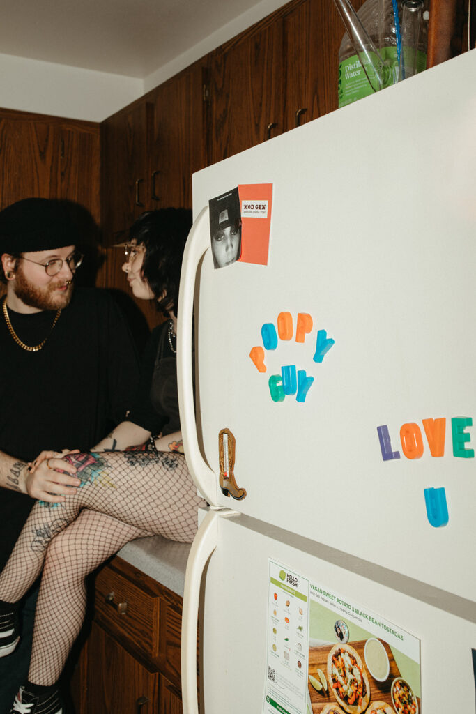 A Wisconsin couple are seated on their kitchen counter during engagement photos in Milwaukee. 