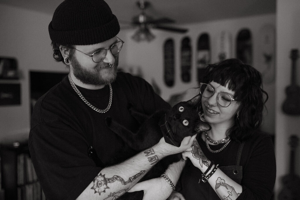 A black and white image of a couple holding their cat in their home during engagement photos in Milwaukee, WI. 