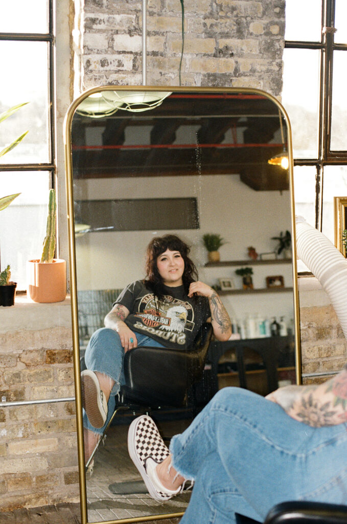 Lady Luck Salon owner, Allie, smiles in a mirror at the salon during a branding session with Wisconsin photographer for creative brands. 