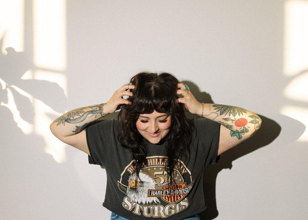 A hairstylist who specializes in edgy hair smiles in a photo taken during brand photos in wisconsin. 