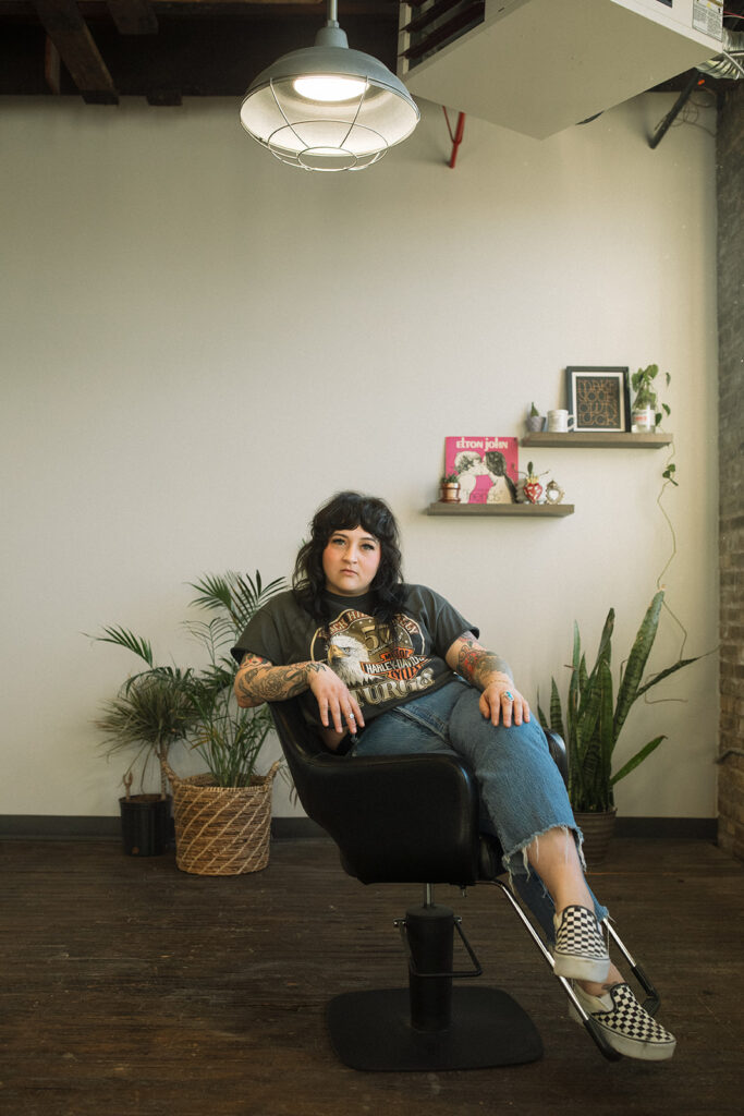 A hairstylist is seated in her salon chair during a brand session with a Milwaukee headshot photographer. 