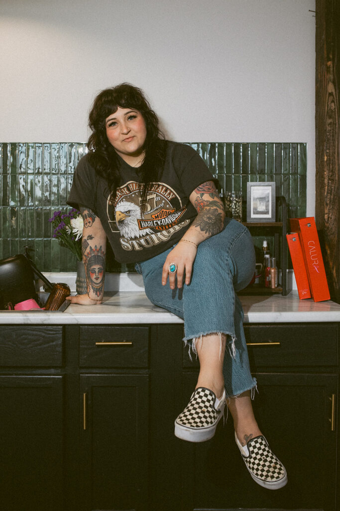 A hairstylist is seated on a salon counter during a brand session with a Wisconsin photographer for creatives. 