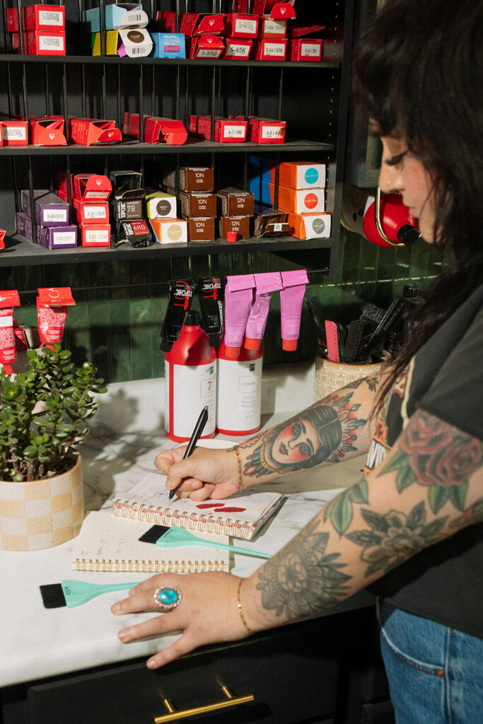A Milwaukee hairstylist writes down color formulations during a brand session with a Wisconsin photographer for creatives. 