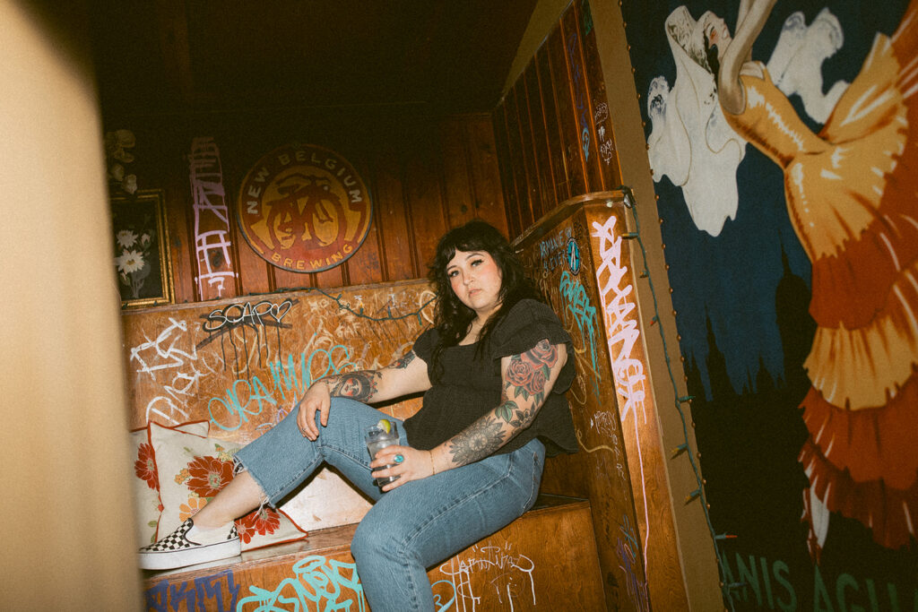 A hairstylist is seated in a booth at Burnhearts during a personal branding session with a Milwaukee headshot photographer. 
