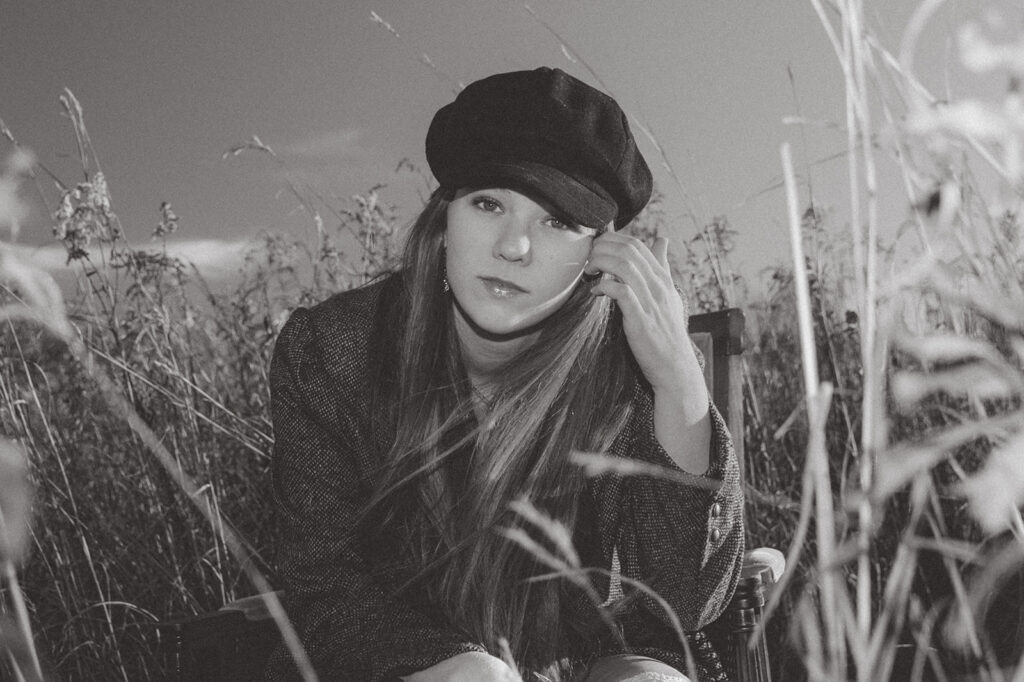 A black and white image of a young woman in an early 2000s newsboy cap taken during her Minnesota Senior Photo session 