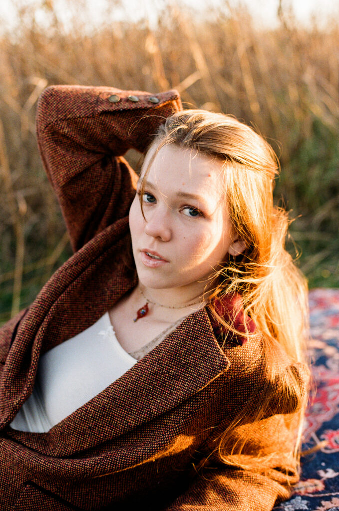 A young woman brushes her hair back in a film image taken during senior photos with a Minnesota senior photographer 