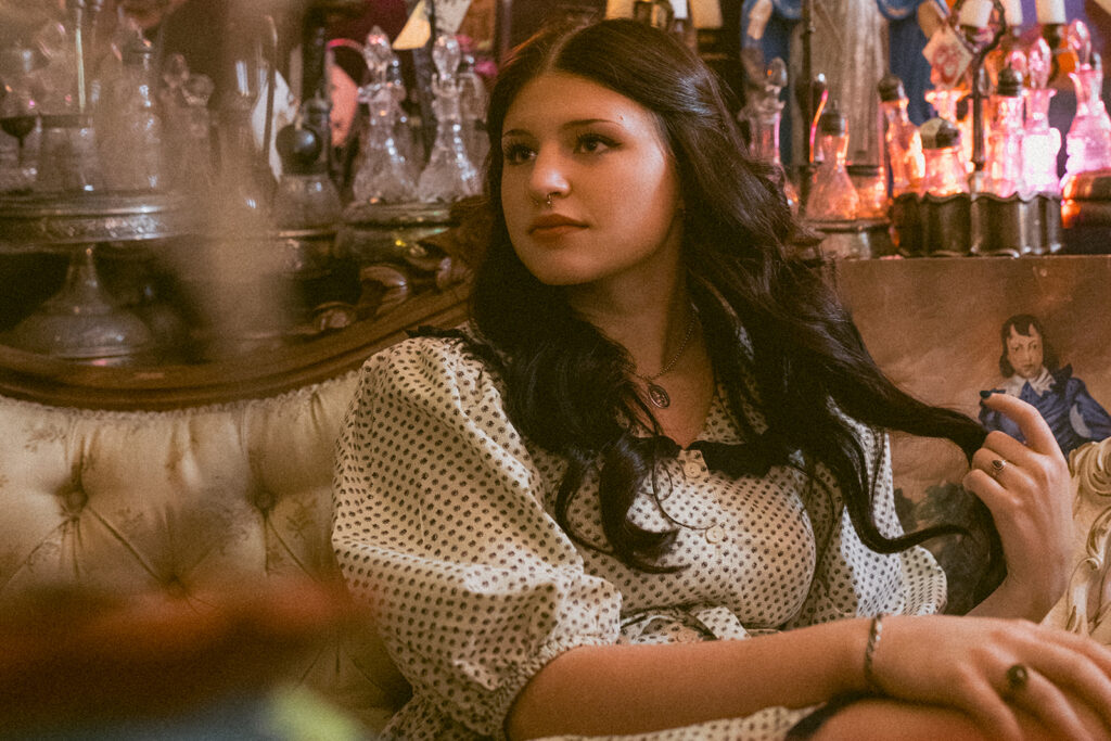 A young woman is seated on an antique couch at a local antique store during senior pictures in Minneapolis.