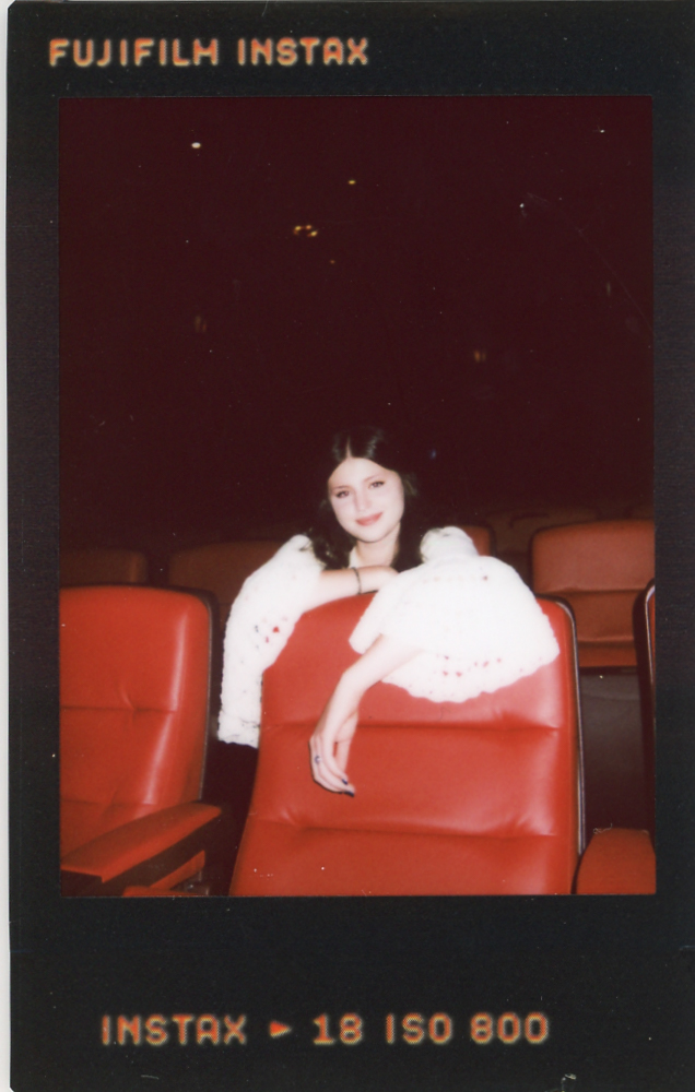 Instax film shows a high school senior leaning over the red seats of The Heights Theater during a senior photoshoot with a Minnesota senior photographer.