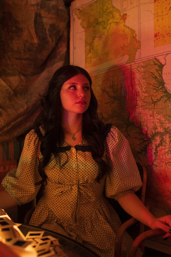 A young woman is photographed amongst vintage maps during senior pictures in Minnesota.