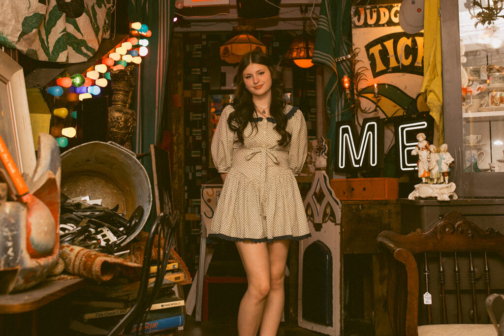 A young woman poses in Hunt & Gather Antiques for Senior pictures in Minnesota.
