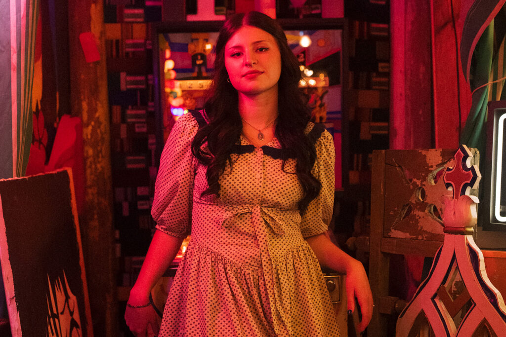 A high school senior girl wearing a polka dot dress poses in Hunt & Gather Antiques during senior pictures in Minnesota.